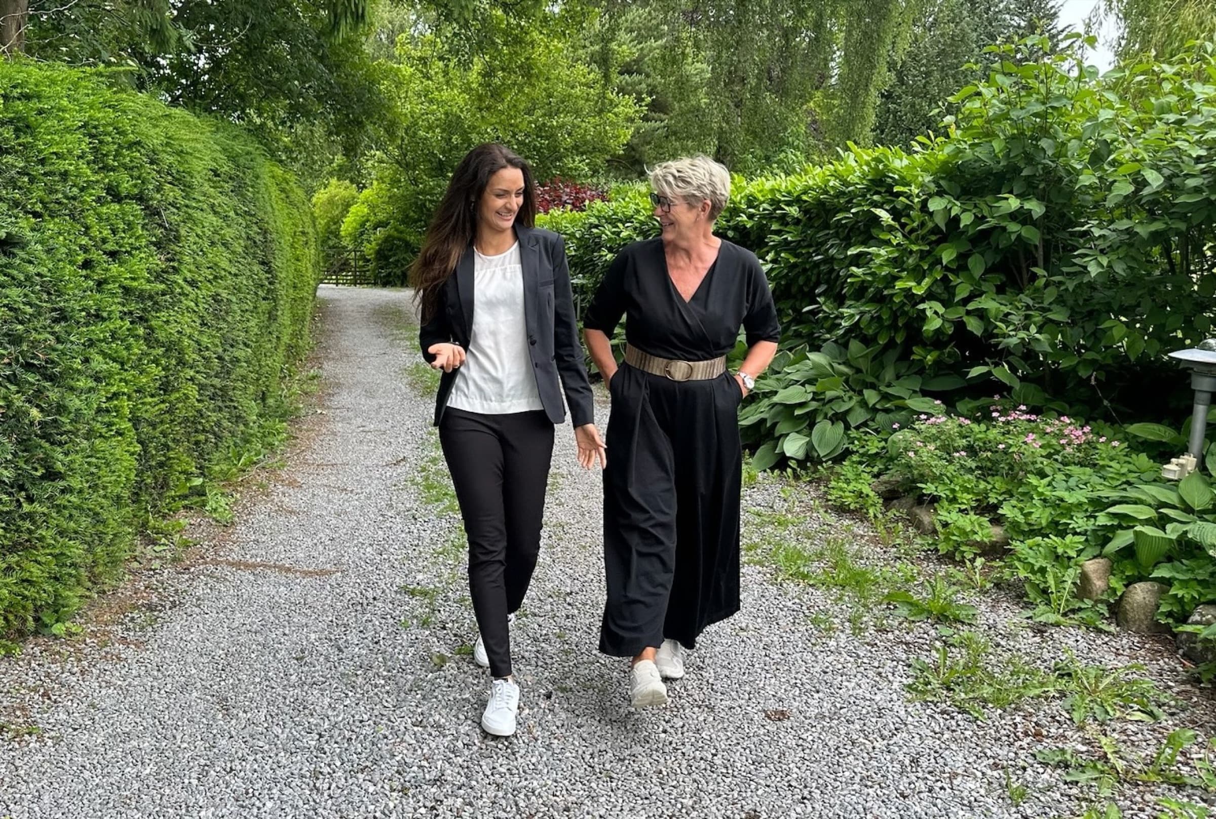 To kvinder går og taler sammen ad en grusvej